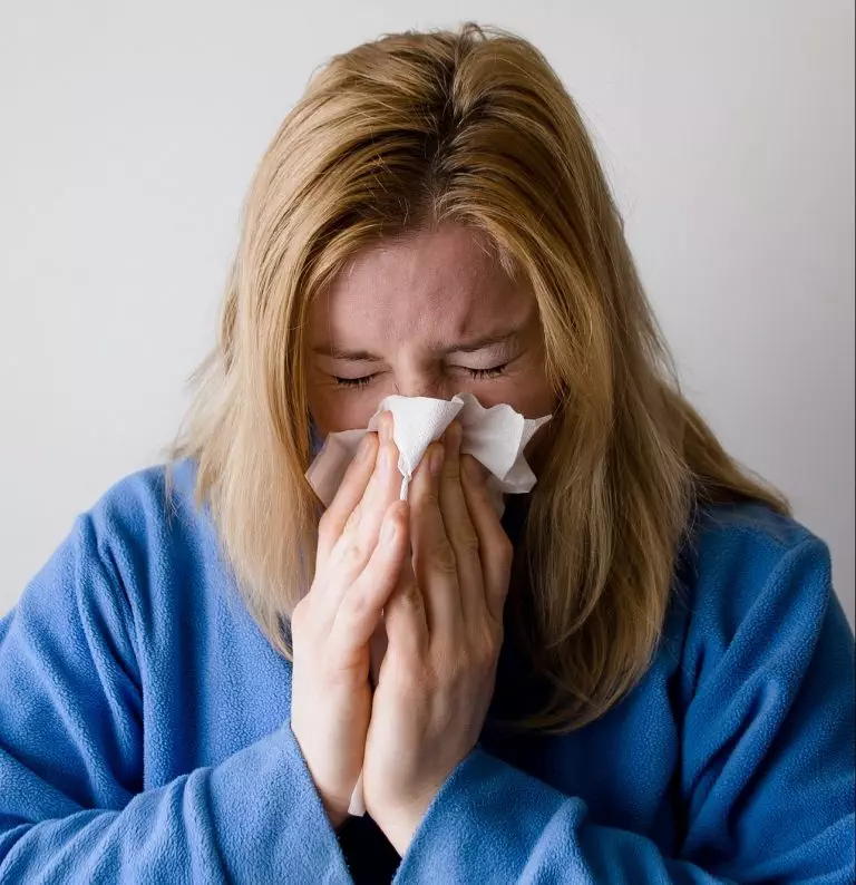 A woman blowing her nose with a tissue while understanding the Families First Coronavirus Response Act.